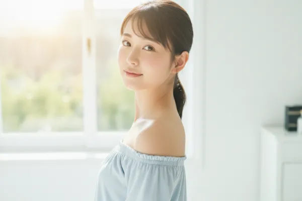 透明感のある純粋無垢な感じの女性が朝の光を背景にして笑顔でこちらを見ている